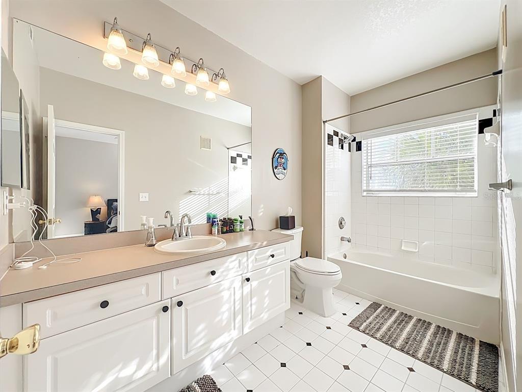 793 Celebration Avenue Celebration, FL 34747 - Photo 19 of 32 a bathroom with a double vanity sink a toilet a mirror and shower