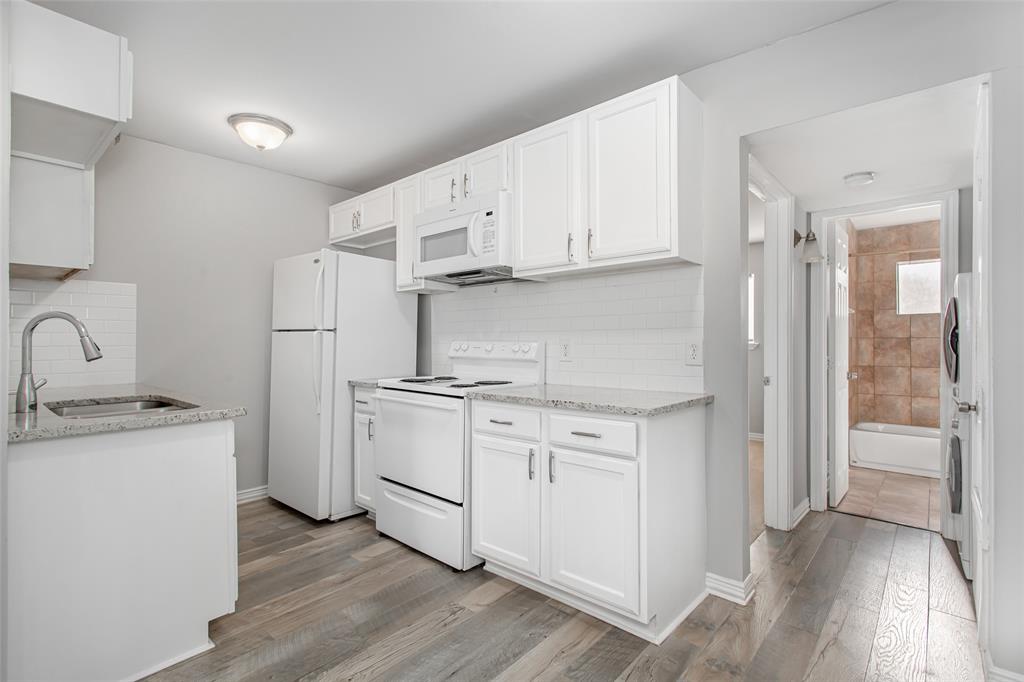 4931 Junius Street, Unit 4 Dallas, TX 75214 - Photo 14 of 31 a kitchen with a sink a stove a refrigerator and white cabinets with wooden floor