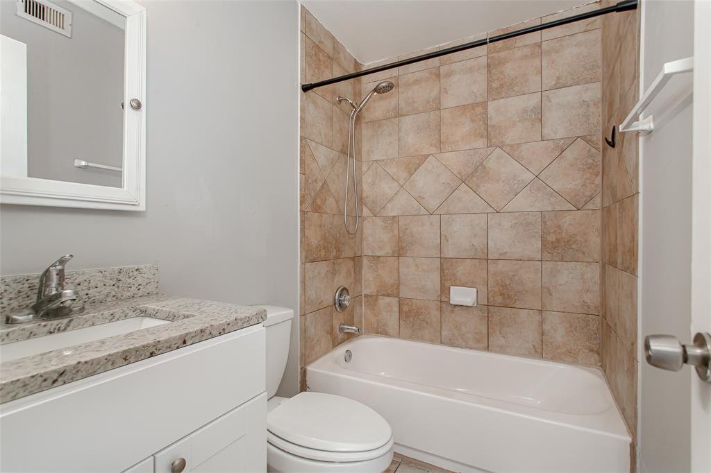 4931 Junius Street, Unit 4 Dallas, TX 75214 - Photo 27 of 31 a bathroom with a granite countertop bathtub shower sink vanity and toilet