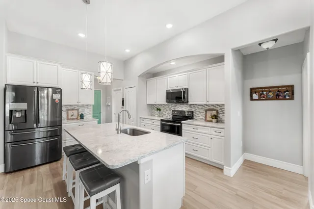 a kitchen with stainless steel appliances granite countertop a sink a stove and a wooden floors