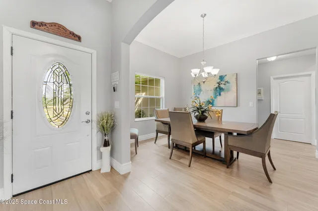 a view of a dining room with furniture a chandelier and wooden floor