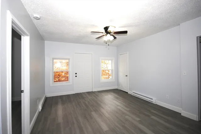 a view of empty room with wooden floor and fan