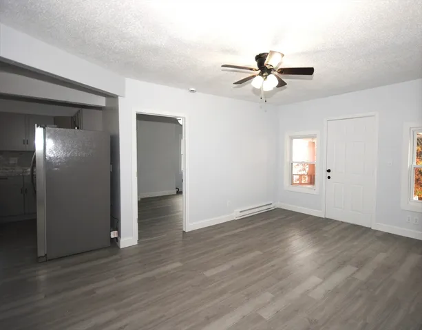 a view of an empty room with wooden floor and a ceiling fan