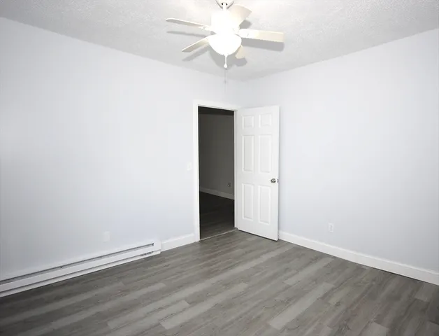 an empty room with wooden floor and fan