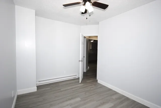 an empty room with wooden floor fan and windows
