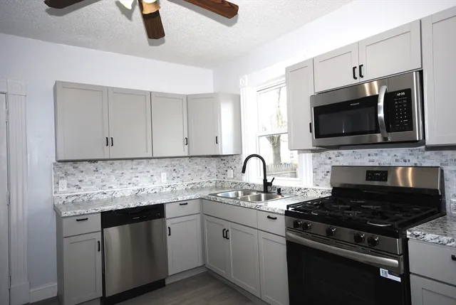 a kitchen with granite countertop a sink stainless steel appliances and cabinets