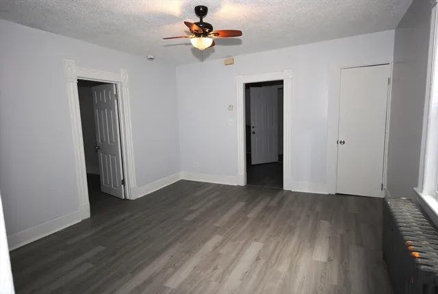an empty room with wooden floor chandelier fan and closet area