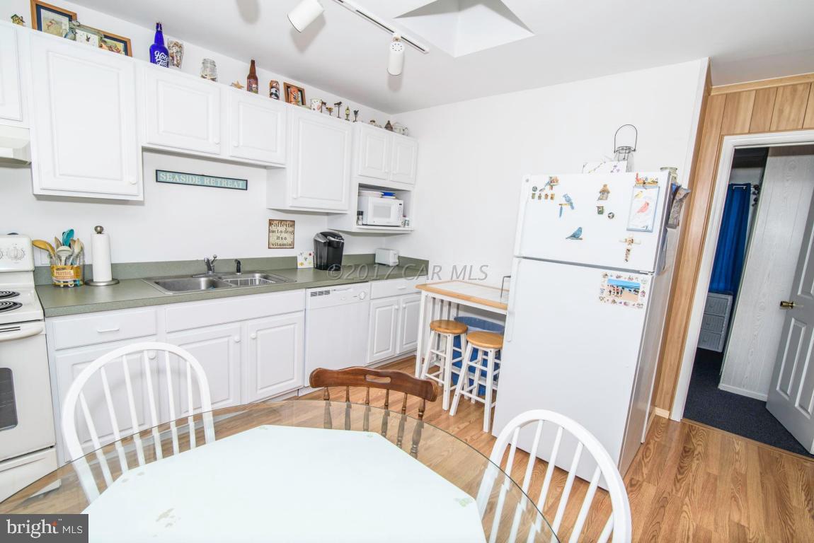 125 Pinehurst Road Ocean Pines, MD 21811 - Photo 11 of 49 a kitchen with stainless steel appliances a white refrigerator a sink dishwasher and white cabinets with wooden floor