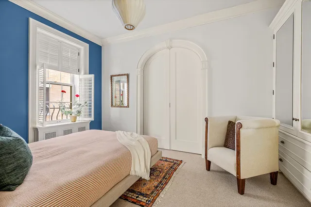 a spacious bedroom with a bed a couch and large window