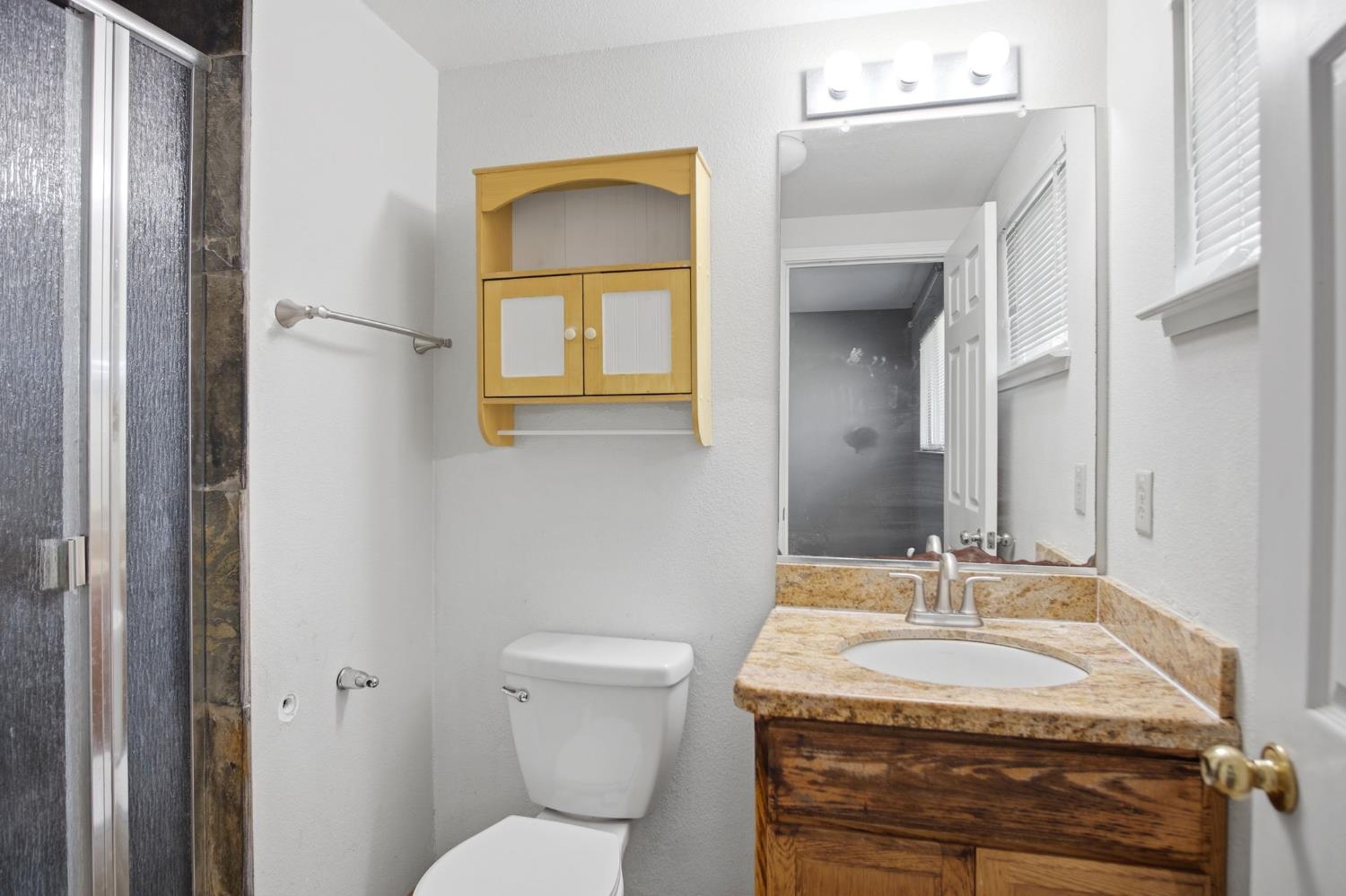 1409 Stonum Road Modesto, CA 95351 - Photo 16 of 40 a bathroom with a granite countertop sink toilet and mirror