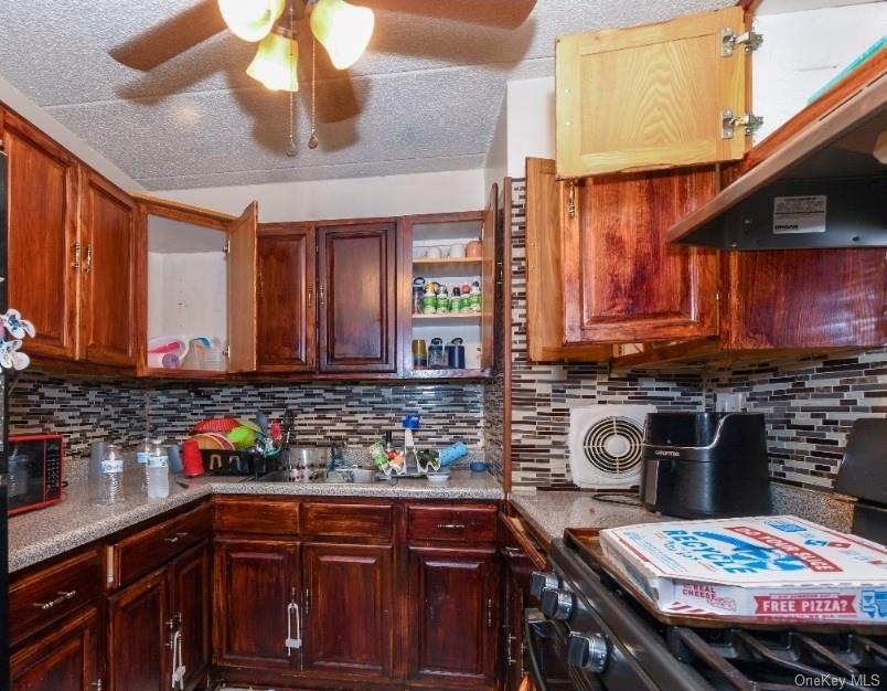 107-41 Sutphin Boulevard Queens, NY 11435 - Photo 13 of 19 Kitchen with tasteful backsplash, range, under cabinet range hood, open shelves, and a textured ceiling