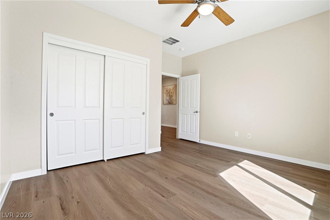 2541 Darda Street Henderson, NV 89044 - Photo 10 of 26 This bright bedroom features a ceiling fan, sliding closet doors, and wood flooring.