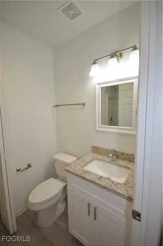 a bathroom with a granite countertop toilet a sink and mirror