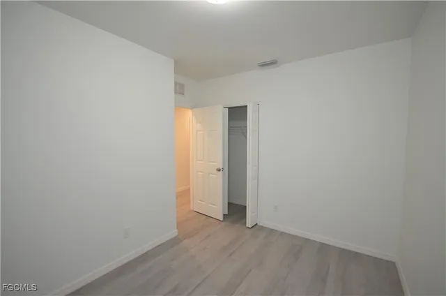 a view of an empty room with wooden floor and closet