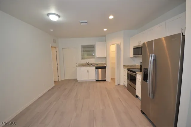 a kitchen with a refrigerator a stove top oven and white cabinets