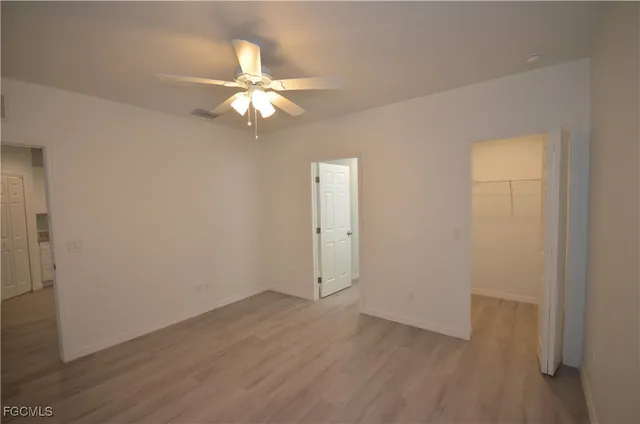 an empty room with wooden floor fan and window
