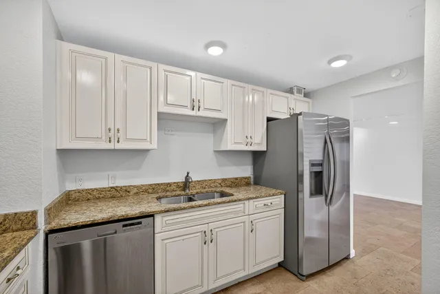 a kitchen with stainless steel appliances granite countertop a refrigerator and a sink