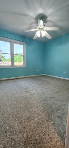 a view of an empty room with window and chandelier fan