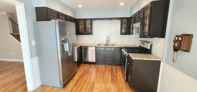 a kitchen with stainless steel appliances a refrigerator sink and wooden floor