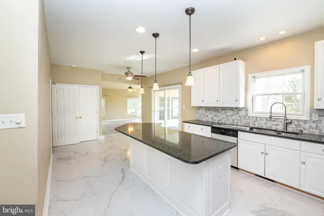 a large kitchen with granite countertop a sink a counter space appliances and cabinets