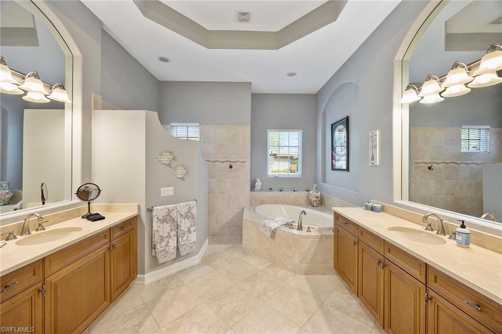 8902 Shenendoah Circle Naples, FL 34113 - Photo 14 of 28 a large bathroom with a double vanity sink large mirror and a bathtub