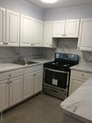 a kitchen with granite countertop white cabinets and a stove