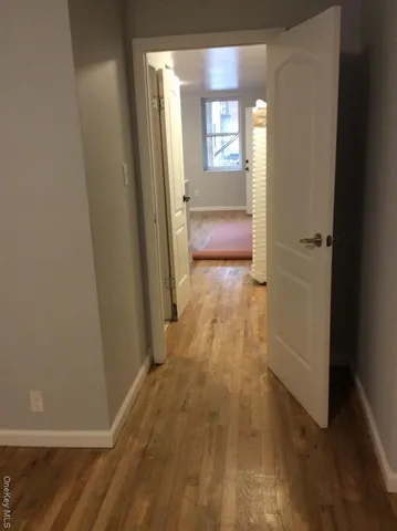a view of hallway with a window and wooden floor