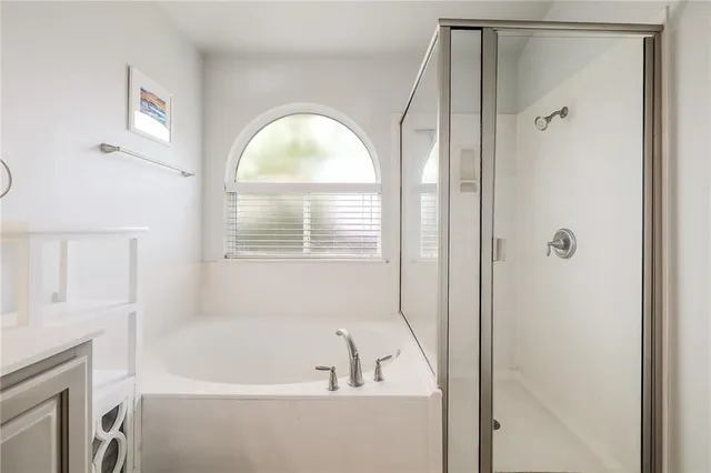 a bathroom with a bathtub a shower and a window