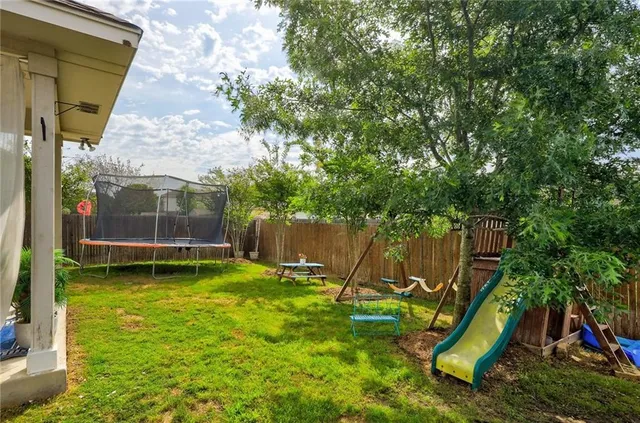 a view of a backyard with a slide trees and wooden fence
