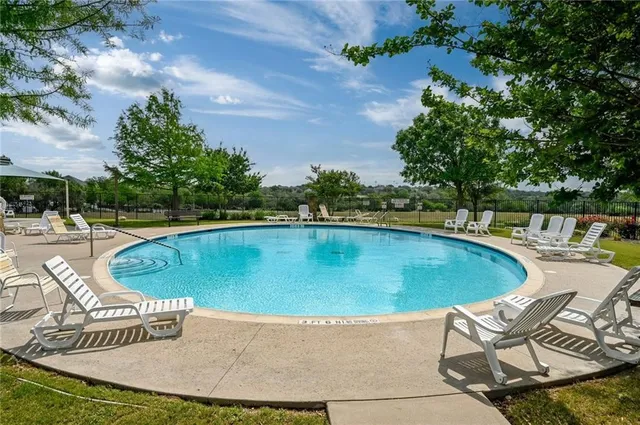 a view of a swimming pool with lawn chairs under an umbrella