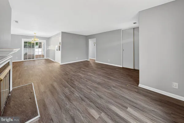 an empty room with wooden floor fireplace and windows