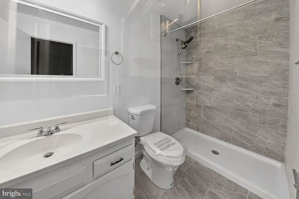 a bathroom with a granite countertop sink a toilet and shower