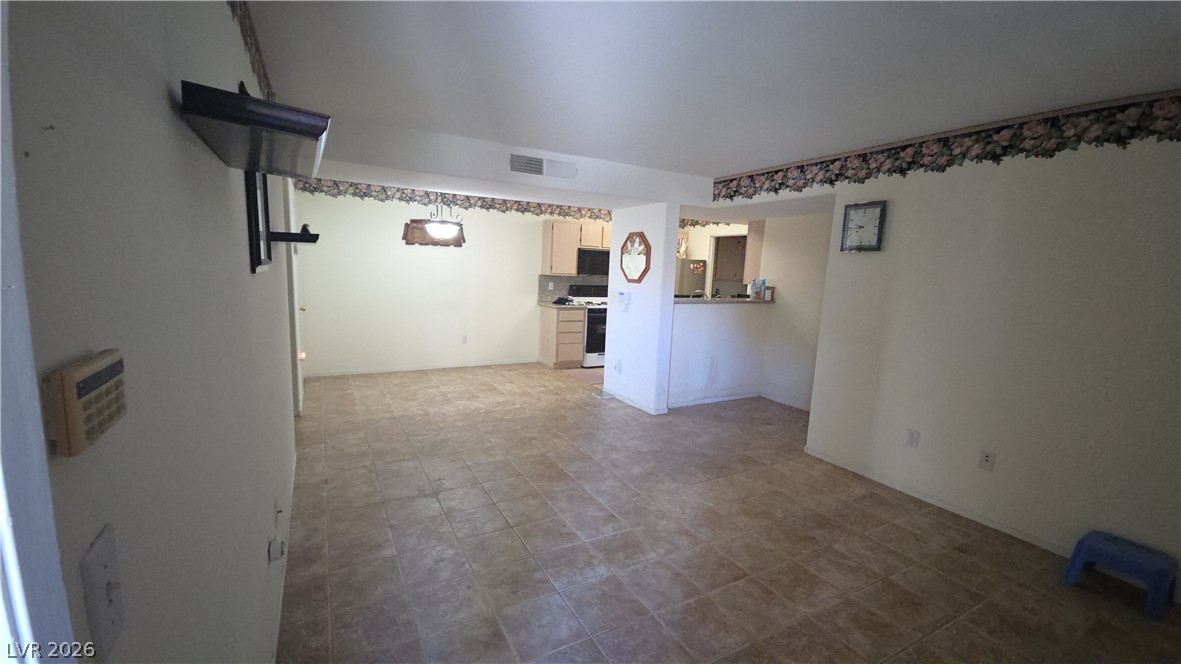 7885 West Flamingo Road, Unit 1008 Las Vegas, NV 89147 - Photo 15 of 29 A well-lit room with durable tile flooring seamlessly transitions into an efficient kitchen area.