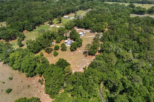 an aerial view of residential house with outdoor space and trees all around