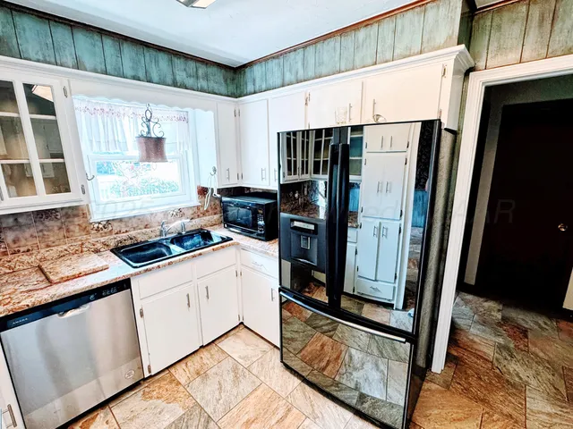 a kitchen with stainless steel appliances granite countertop a refrigerator a stove and a sink