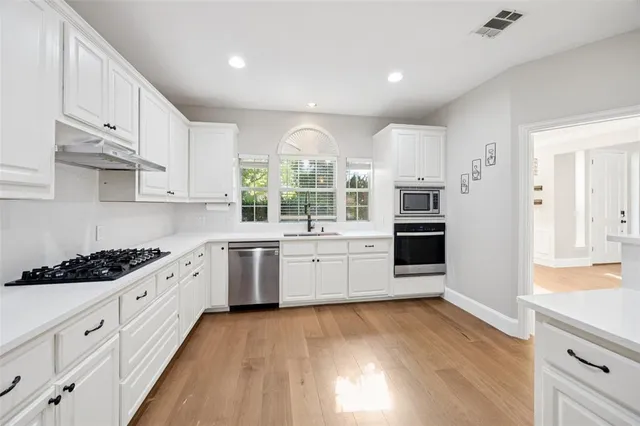 a large kitchen with a lot of counter space and wooden floor