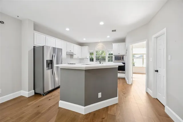 a kitchen with stainless steel appliances kitchen island granite countertop a stove a sink and white cabinets with wooden floor