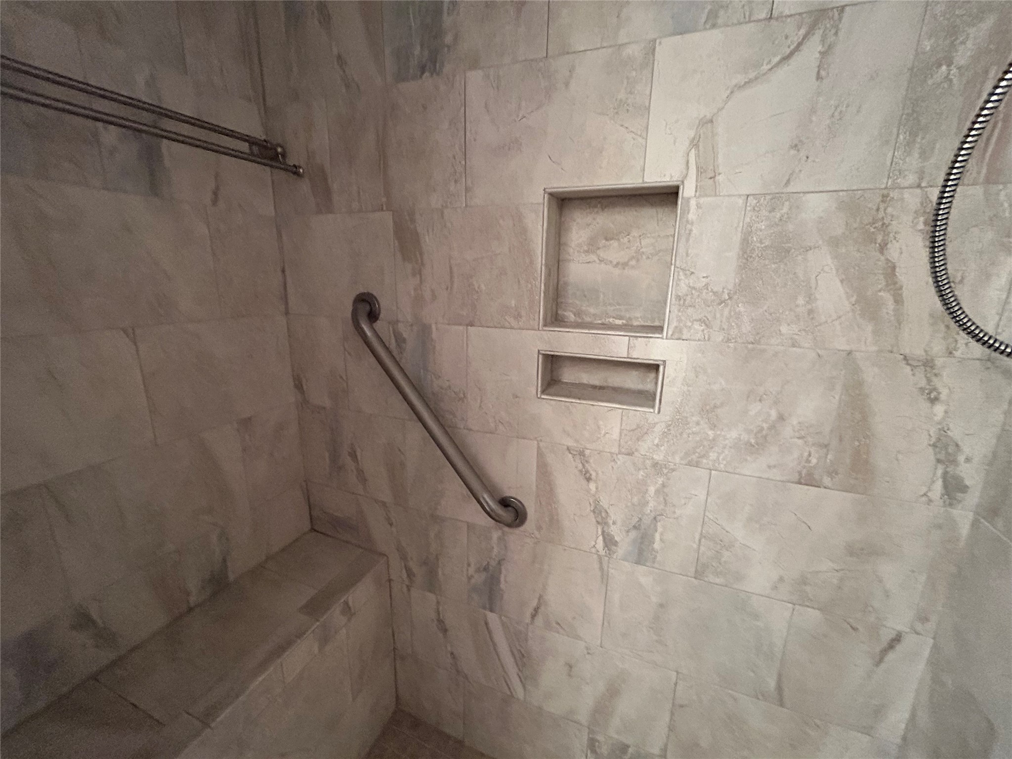 13034 Leader Street, Unit 965 Houston, TX 77072 - Photo 16 of 32 This photo shows a modern shower with beige tiles, a built-in bench, grab bar, and two recessed niches for storage.