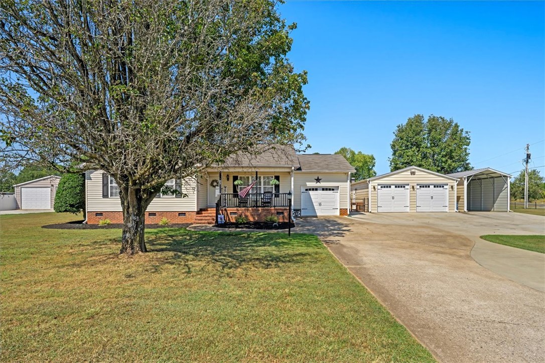 Mature trees frame this ranch-style residence featuring multiple garages and a spacious concrete driveway.