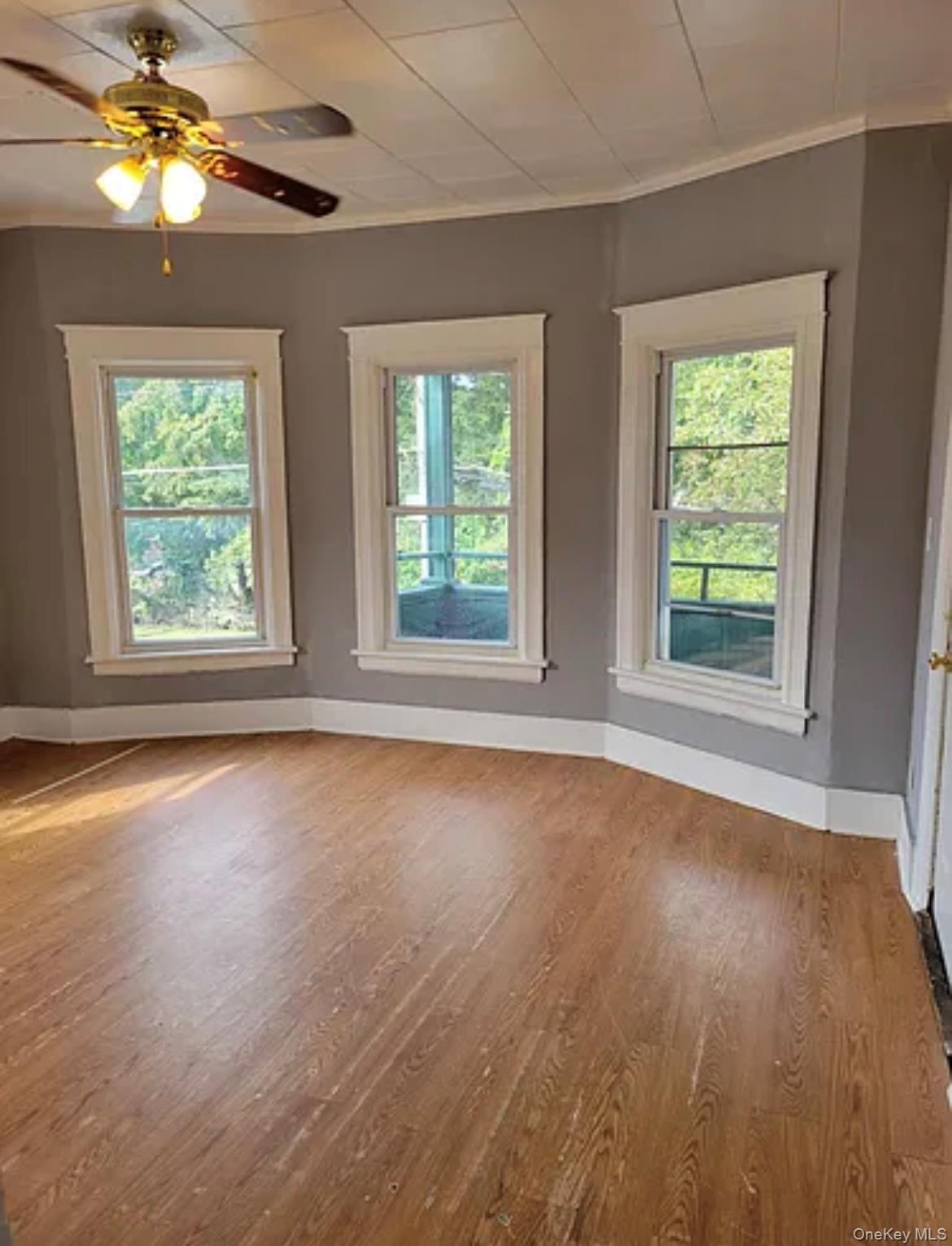 a view of an empty room with a window and wooden floor