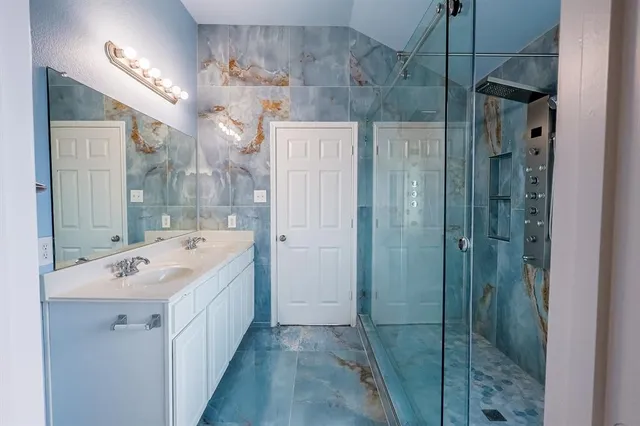 a bathroom with a double vanity sink a large mirror and shower