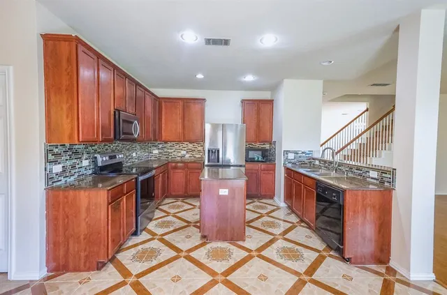 a kitchen with stainless steel appliances granite countertop a stove a sink and a microwave