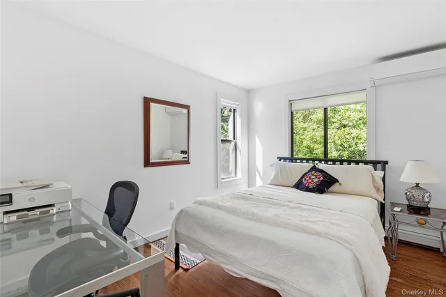 a bedroom with a bed a computer on desk and a dresser next to a window