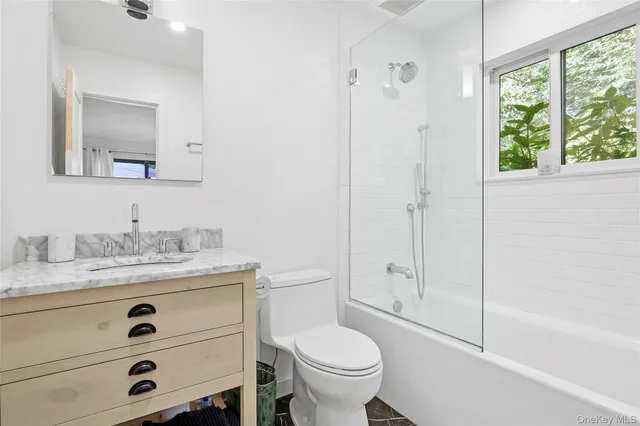 a bathroom with a granite countertop sink toilet and shower