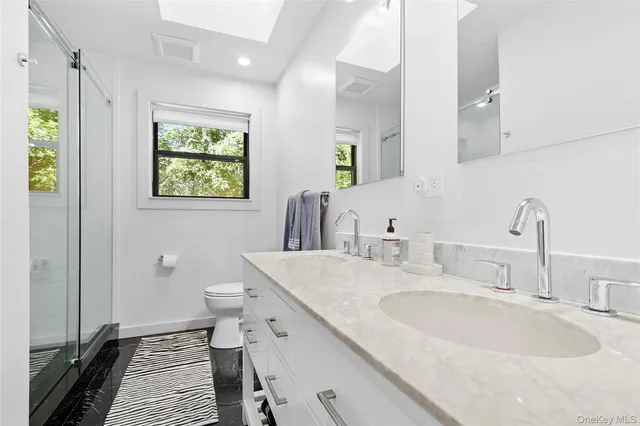 a bathroom with a granite countertop sink a toilet a and a mirror