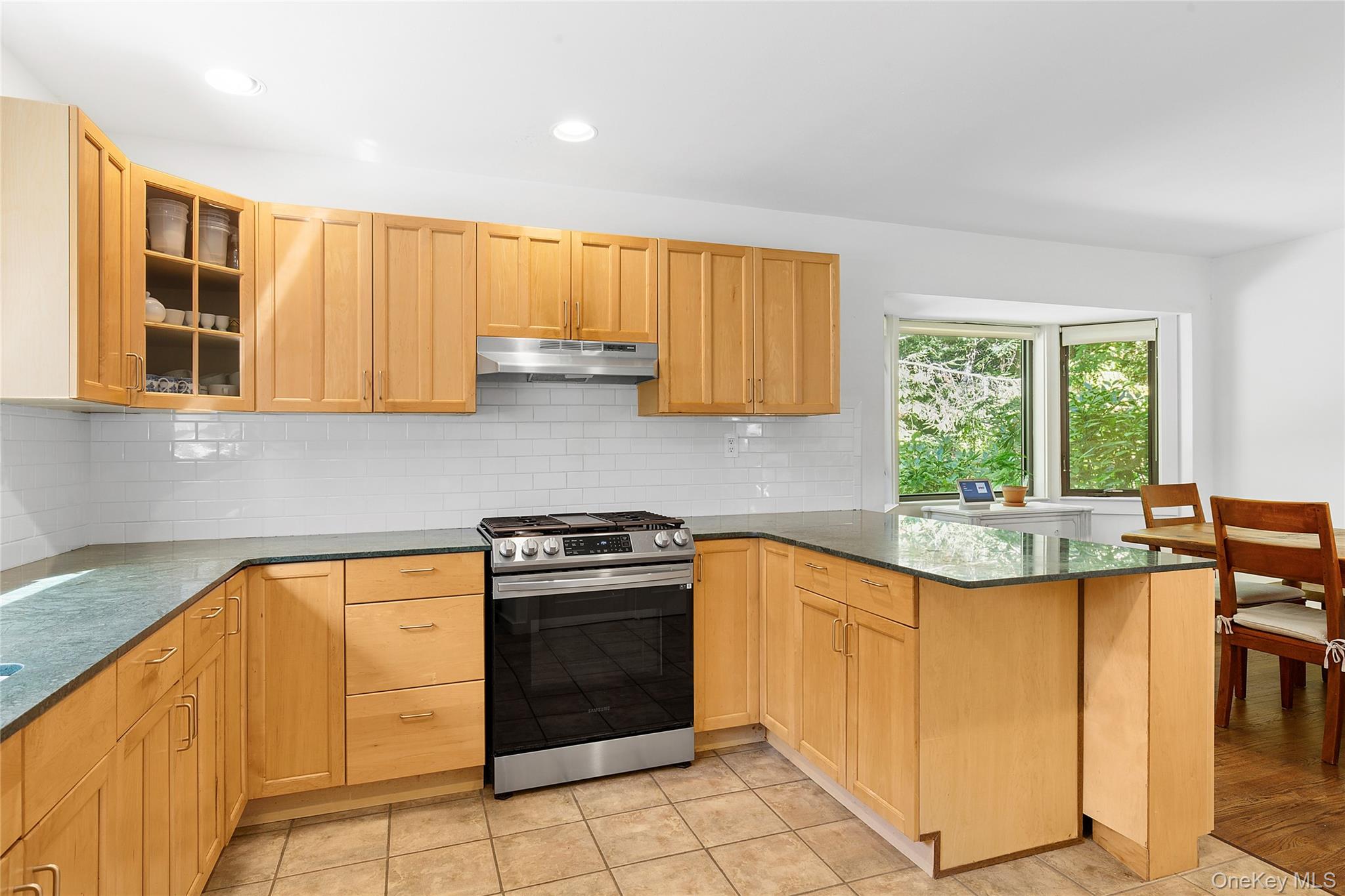 98 Hands Creek Road East Hampton, NY 11937 - Photo 17 of 20 Kitchen featuring dark stone counters, gas stove, a peninsula, tasteful backsplash, and glass insert cabinets