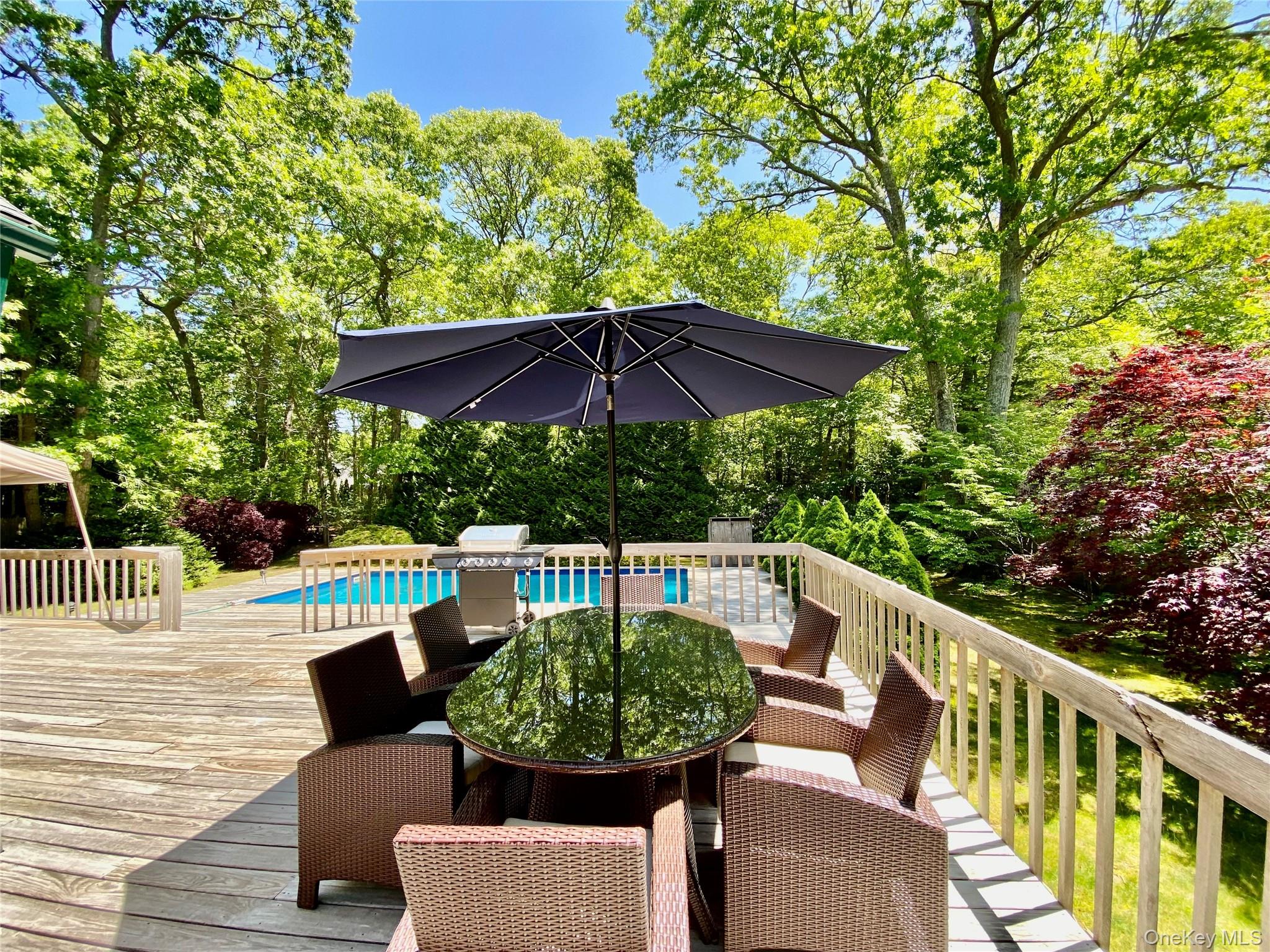 98 Hands Creek Road East Hampton, NY 11937 - Photo 7 of 20 Wooden deck with an outdoor pool, view of scattered trees, area for grilling, and outdoor dining space