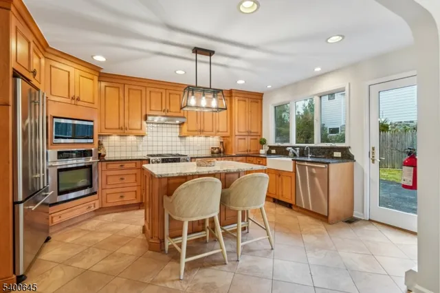 a large kitchen with kitchen island granite countertop a stove a sink a dining table and chairs