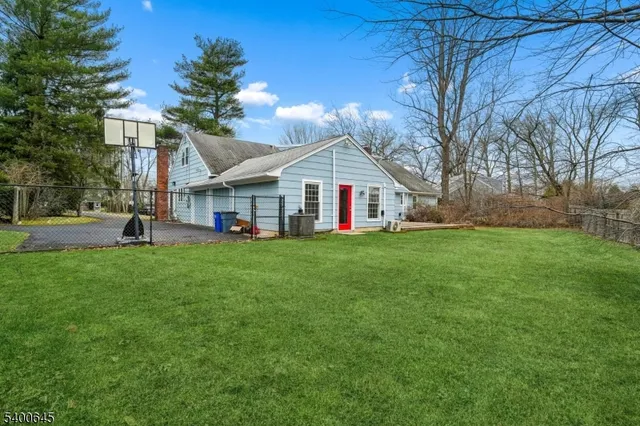 a view of a house next to a big yard and large trees