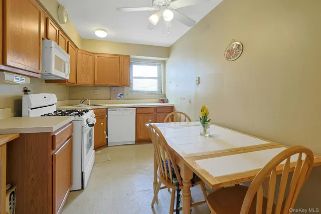 a kitchen with a stove a sink a refrigerator dining table and chairs